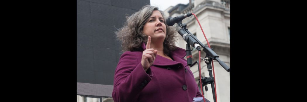 Woman speaking into microphone, finger raised to point