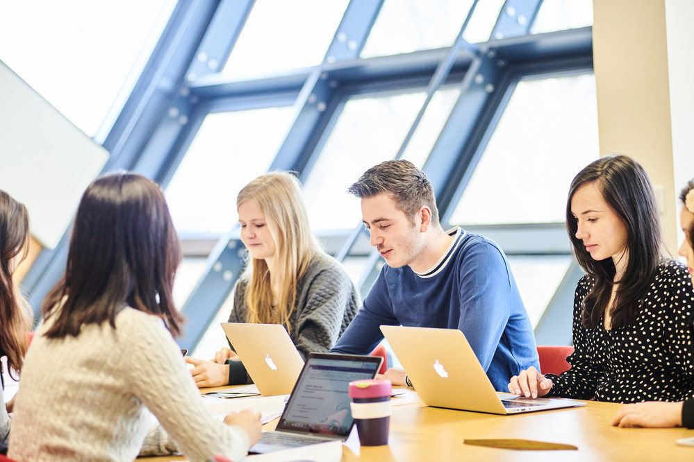 Students sitting around a table on laptops