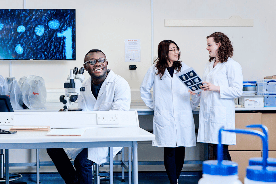 4 students in lab coats in a laboratory
