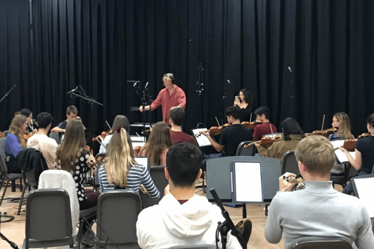 Student orchestra from behind facing a conductor