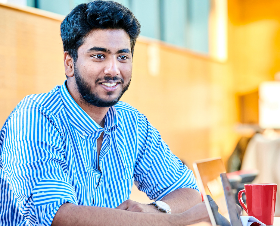 A male student smiling with a laptop