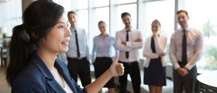 A female lecturer addresses standing business students in corridor