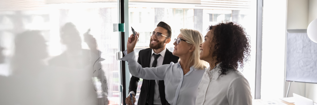 Motivated diverse employees brainstorm develop strategies on whiteboard