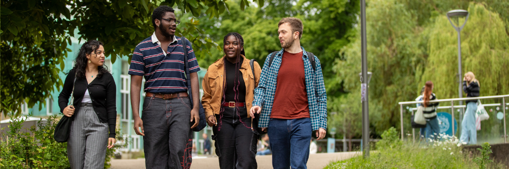 Four students walking by Durham riverside