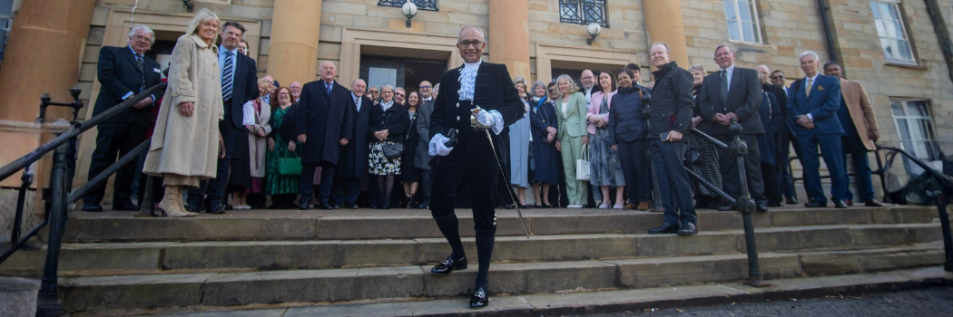 Dr Arnab Basu in front of County Hall after his installation as High Sheriff. He wears ceremonial dress and has a crowd of people behind him