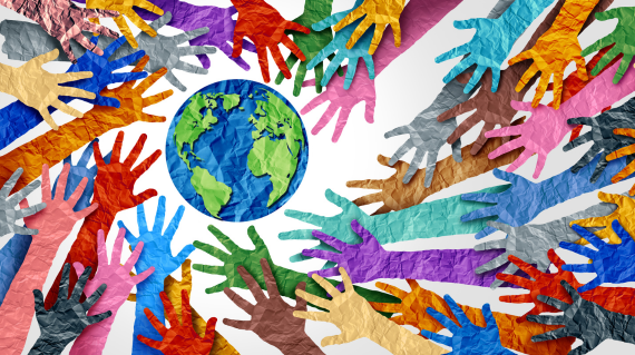 Different coloured hands made from paper surrounding a paper earth