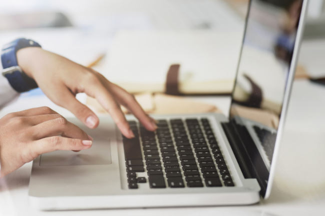 TClose up of hands typing on a laptop