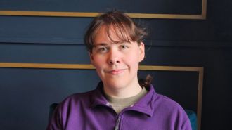 Sam in purple jumper smiling at camera