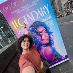 Jennifer Leigh in front of a publicity poster.png
