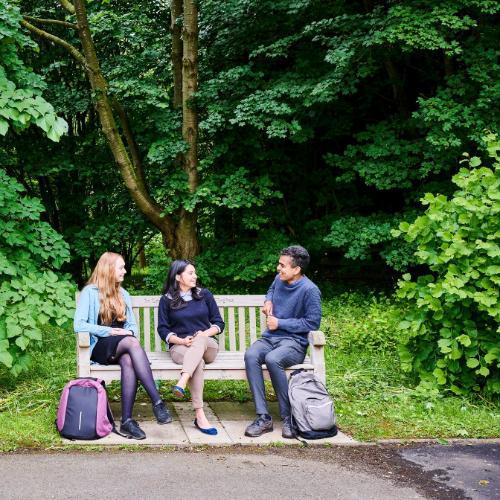 Students sitting on an outdoor bench in the gardens