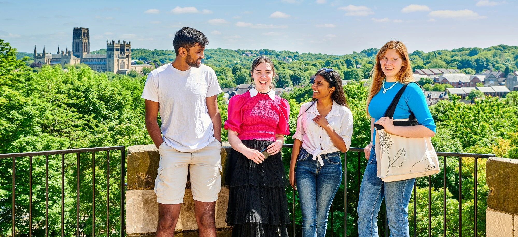 Four students smiling with the Cathedral in distance