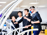 Male student on a treadmill with male and female students watching their male lecturer analysing the breath by breath test