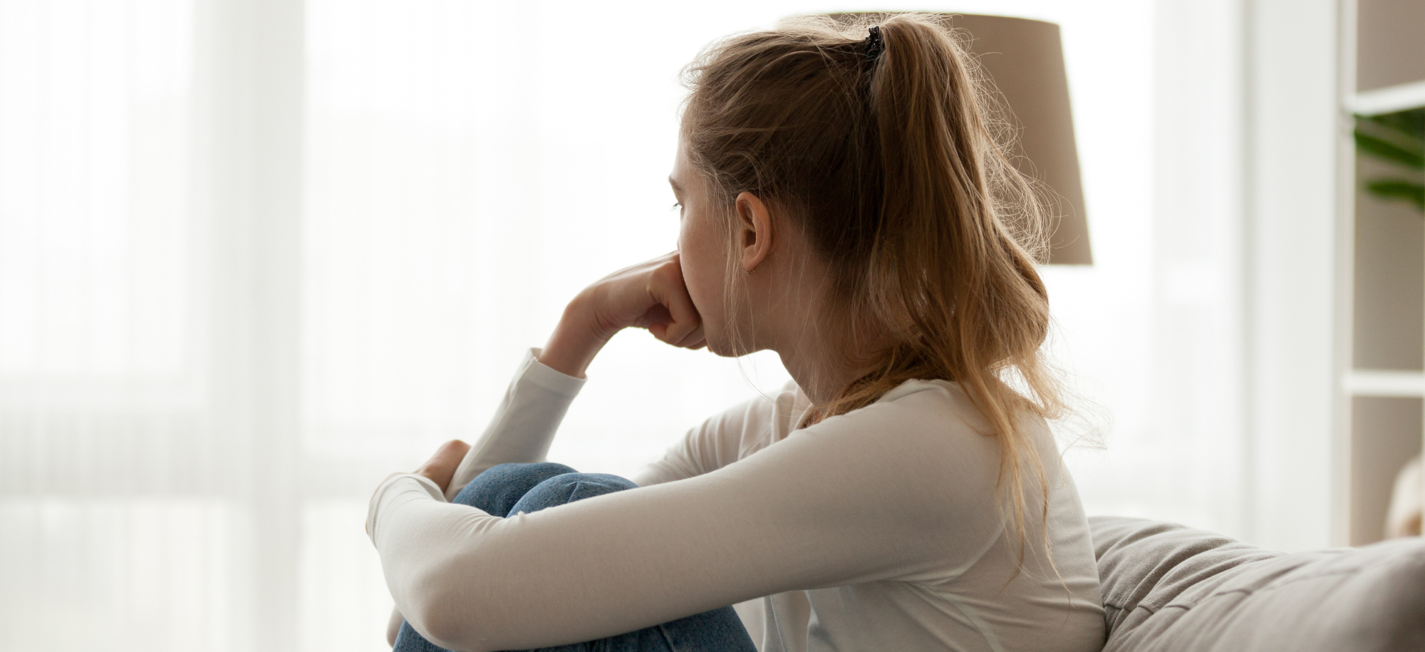 Image of woman sat alone looking out of window