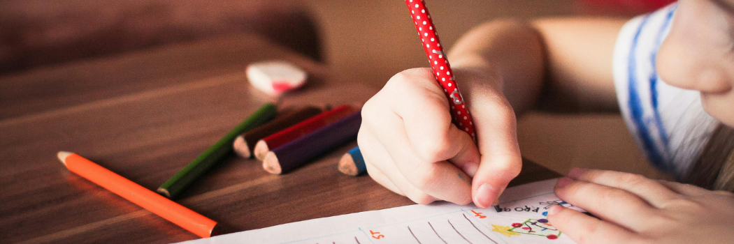 A close up of a child's hand writing in an exercise book.