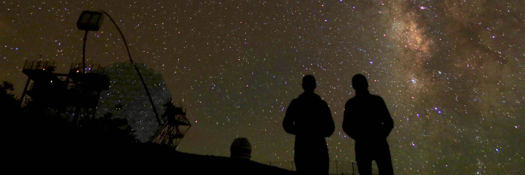 Two people silhouetted against a starry sky.