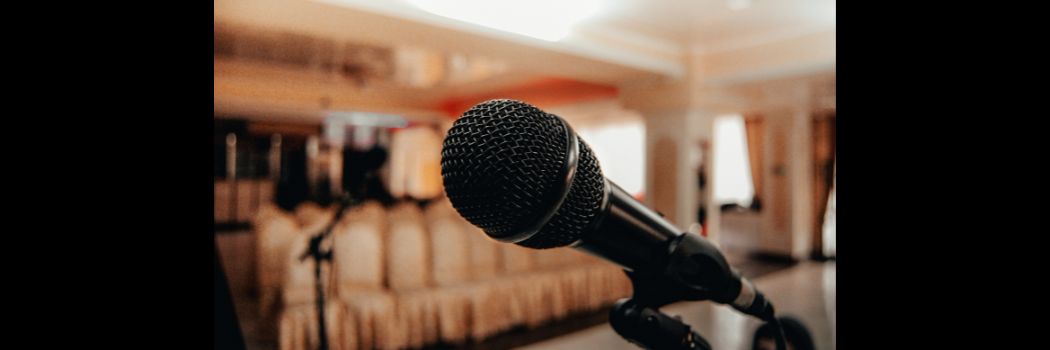 Close-up of a microphone, with well-dressed chairs in background