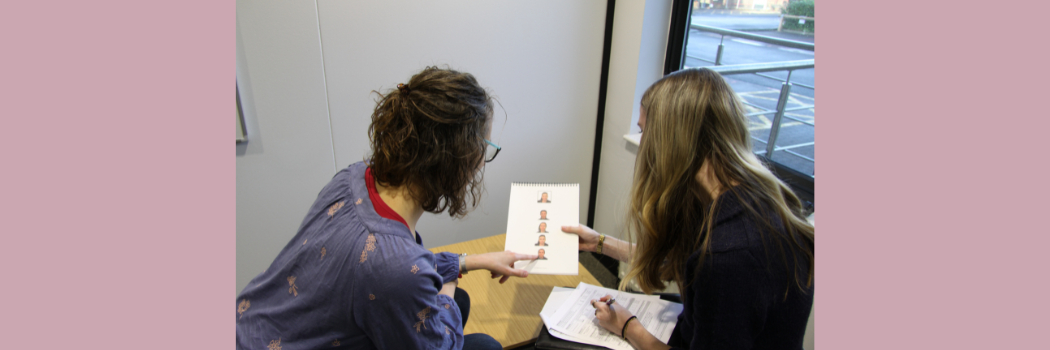 Two people sitting at a table pointing at a page in the stroke screening booklet.