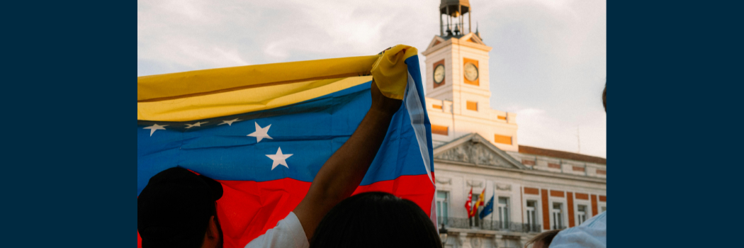 A man holding the Venezuelan flag in front of a building.