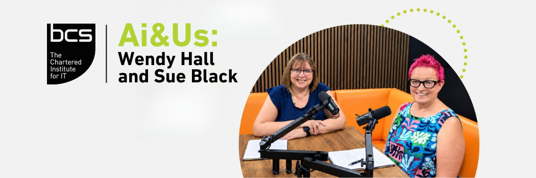 Two women sit at a table with microphones.