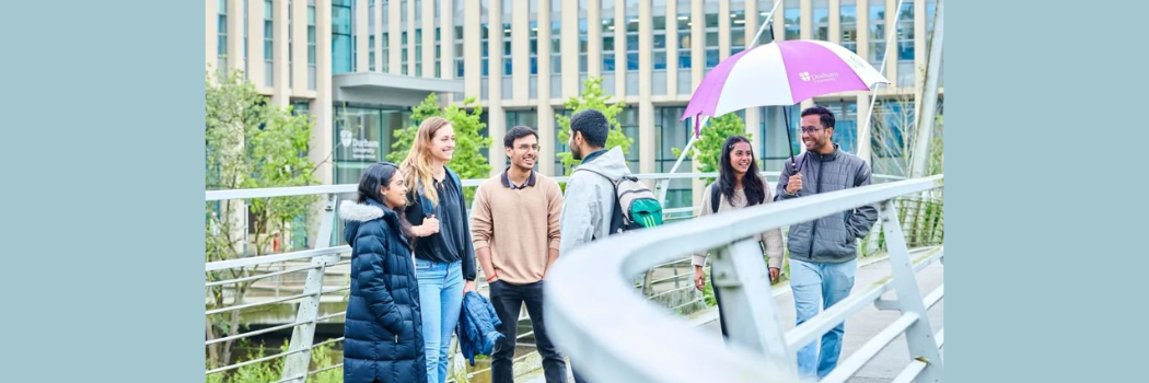 A group of students standing on a bridge smiling and talking