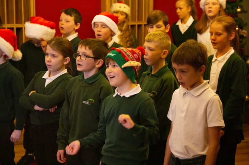 A group of children dressed in Christmas accessories singing in recording studio at Collingwood