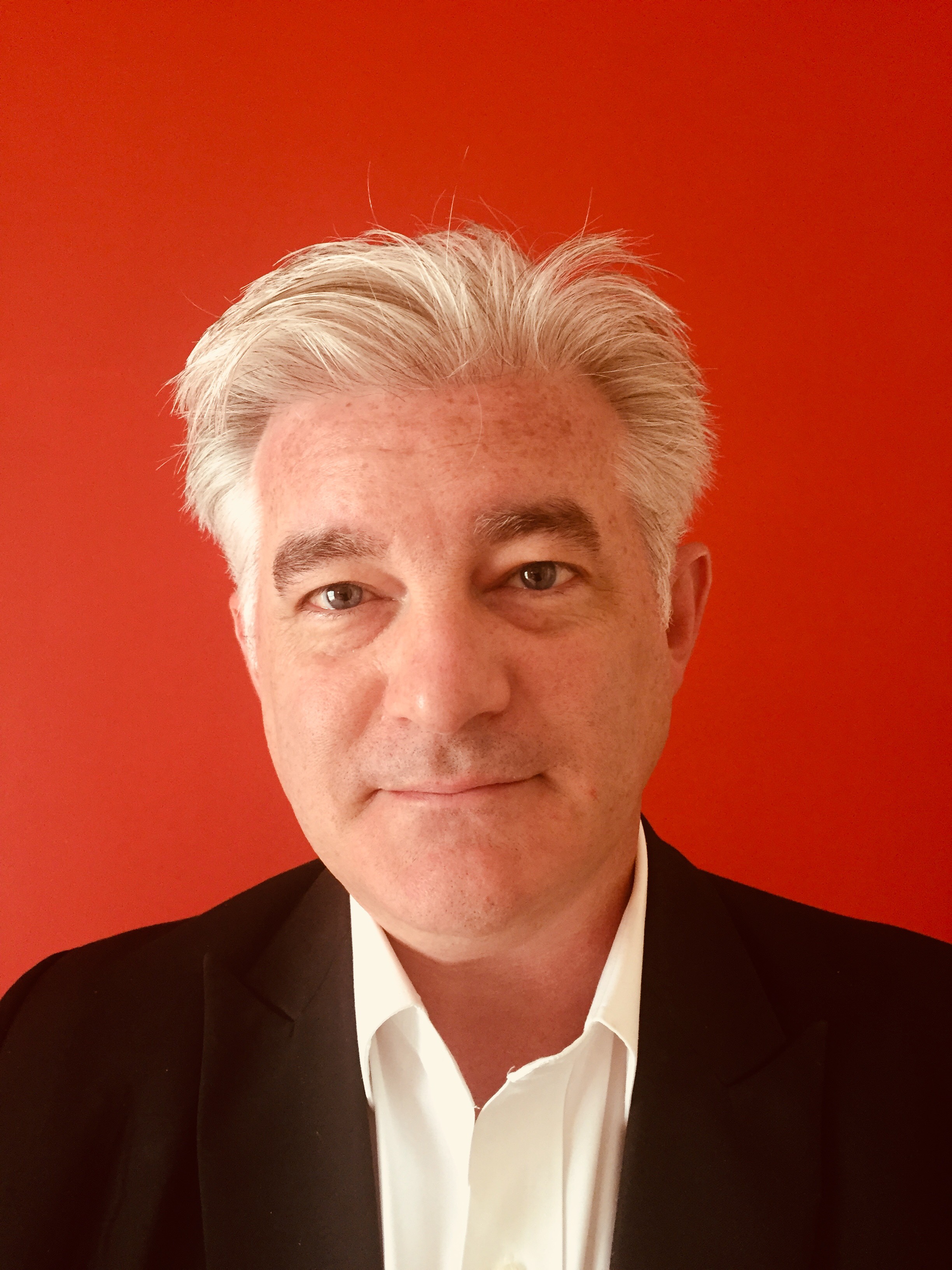 A headshot of Jonathan Fulton with a red background