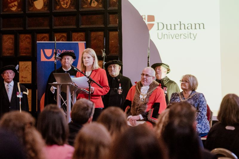 Claire O'Malley standing at a lecturn addressing a room full of people at the civic welcome for International students