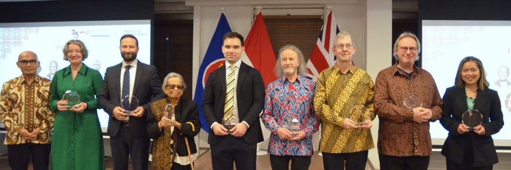 People standing in front of flags, some with awards