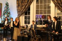 Students performing in a musical ensemble with a window and a Christmas tree in the background