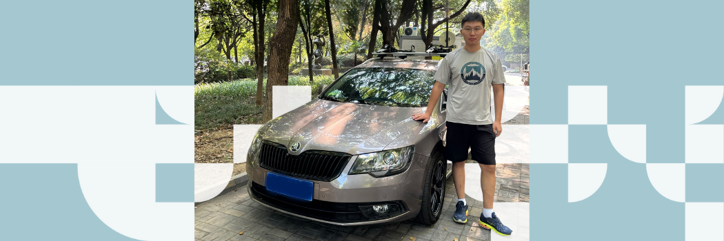 A young man in shorts, t-shirt and trainers standing to the right of a silver car with his hand on the bonnet