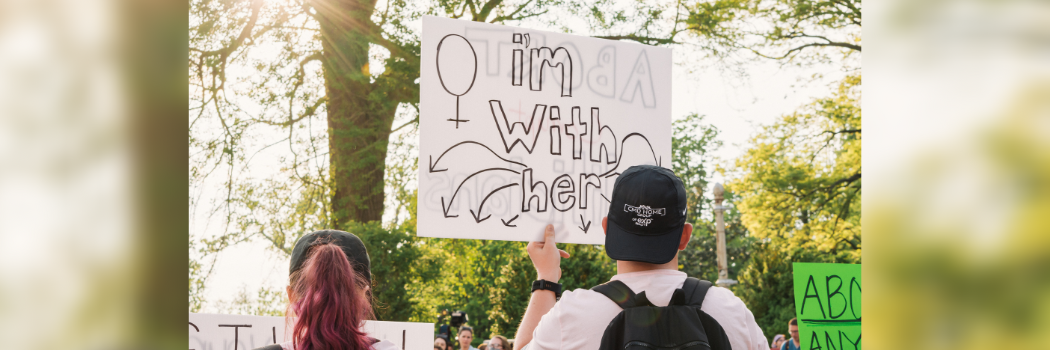 A man holds a sign at a protest reading 