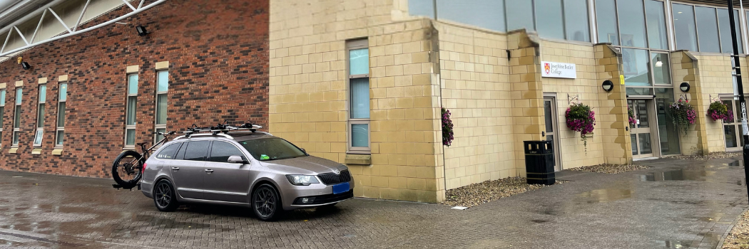 A silver car with a bike on the back parked outside of Josephine Butler College