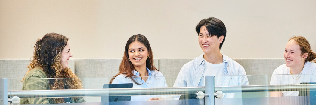 Students talking and smiling at a high table in Durham University Business School