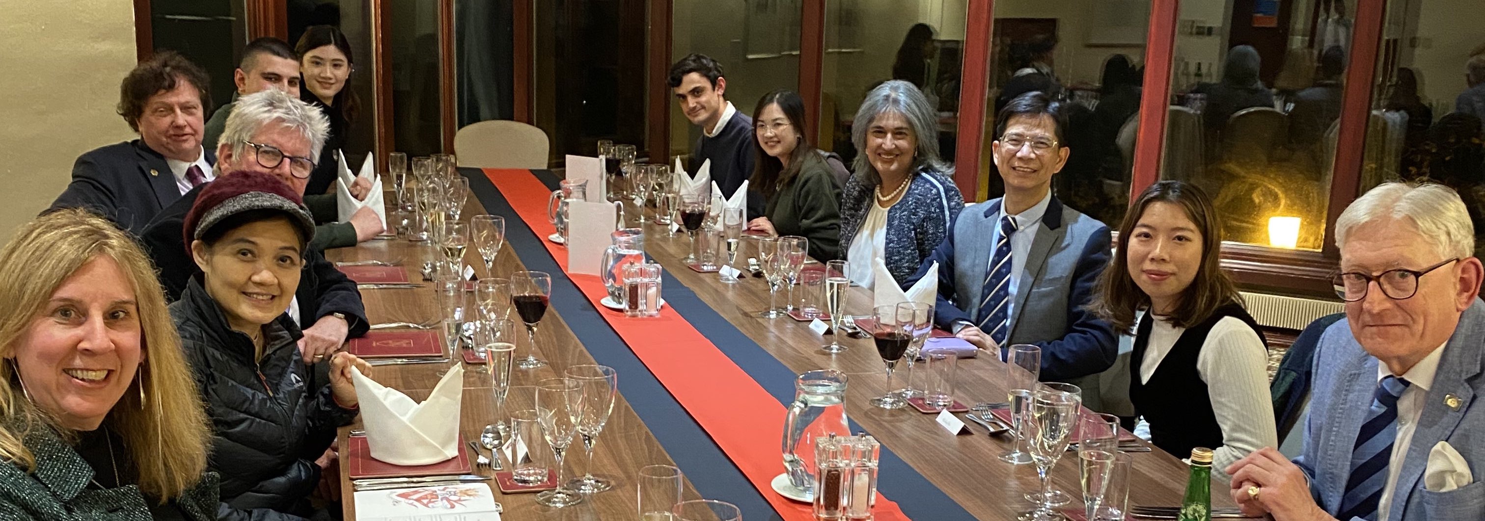 Students, staff and guests sitting at a formal dinner table.