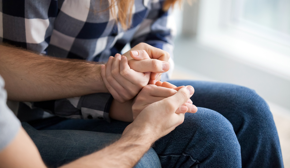 People reassuringly holding hands with one another