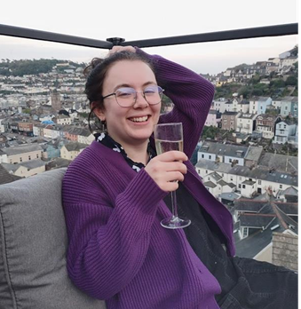 Melody sitting with their arm raised and wine glass in hand