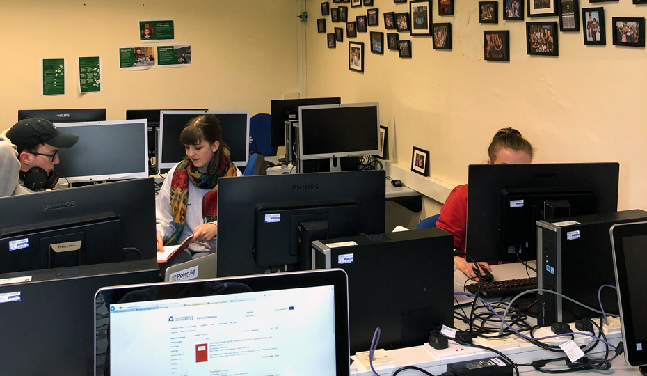 Students using desktop computers in the computer room, the walls are decorated with pictures.