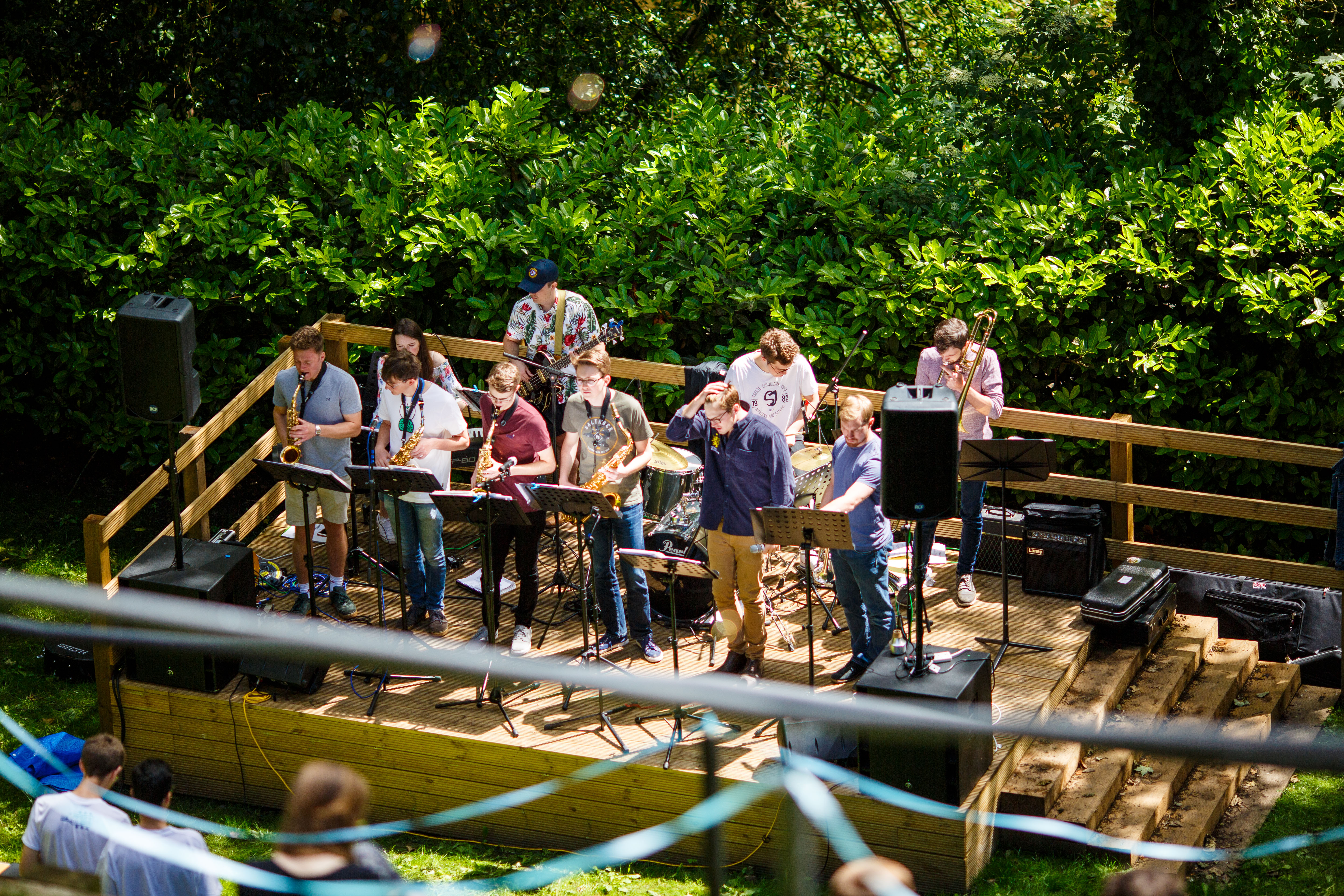 Students playing musical instruments on a wooden outdoor stage