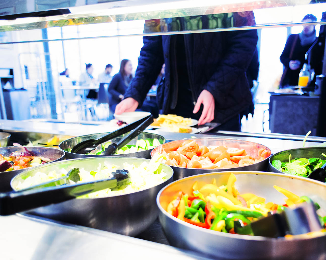 Student helping themselves to salad at a buffet