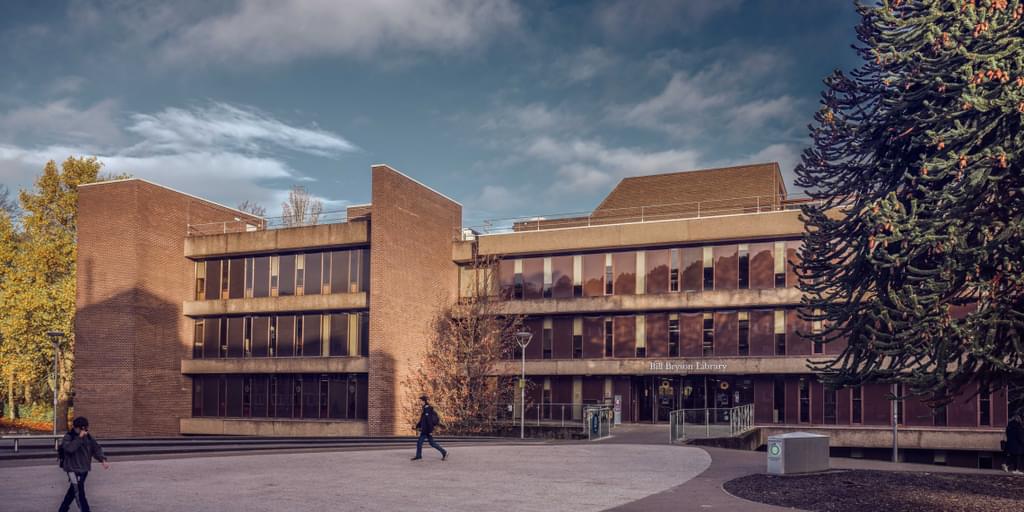 External shot of the Bill Bryson Library main entrance - no close-ups of people. Trees look autumnal and the sky is cloudy.