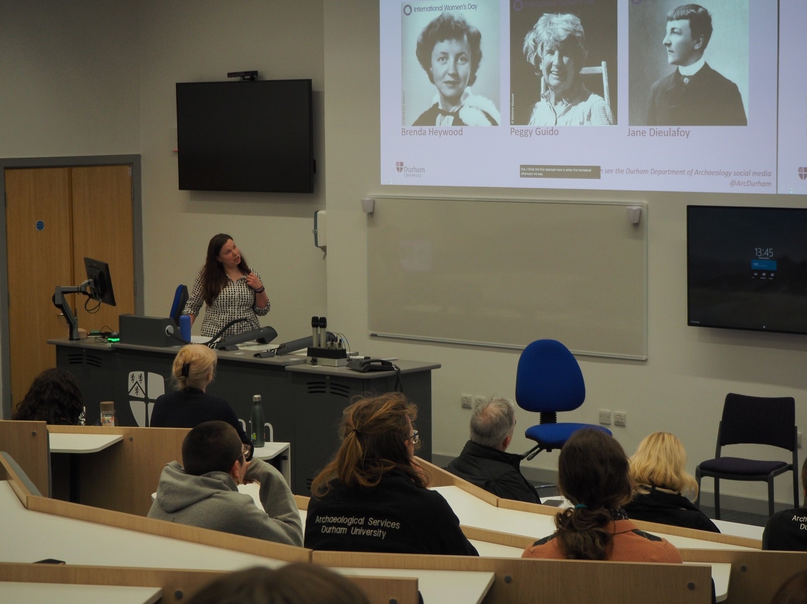 A woman presenting in front of students on International Women's Day