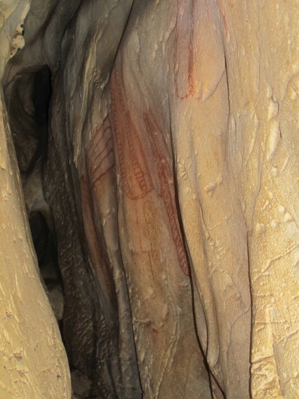 Red patterns known as tectiform motifs painted in a cave wall