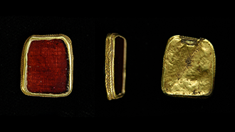 Front, side and back images of a red stone jewel in gold casing