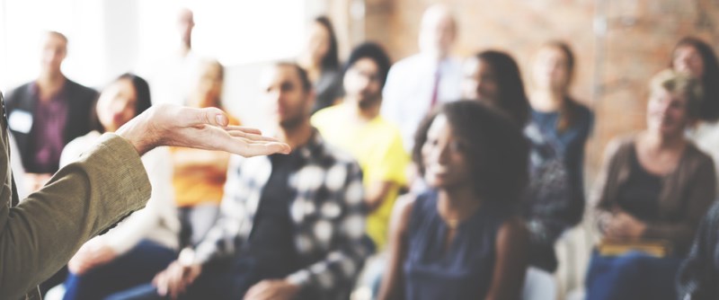 Blurry image of classroom with students with focus on a hand