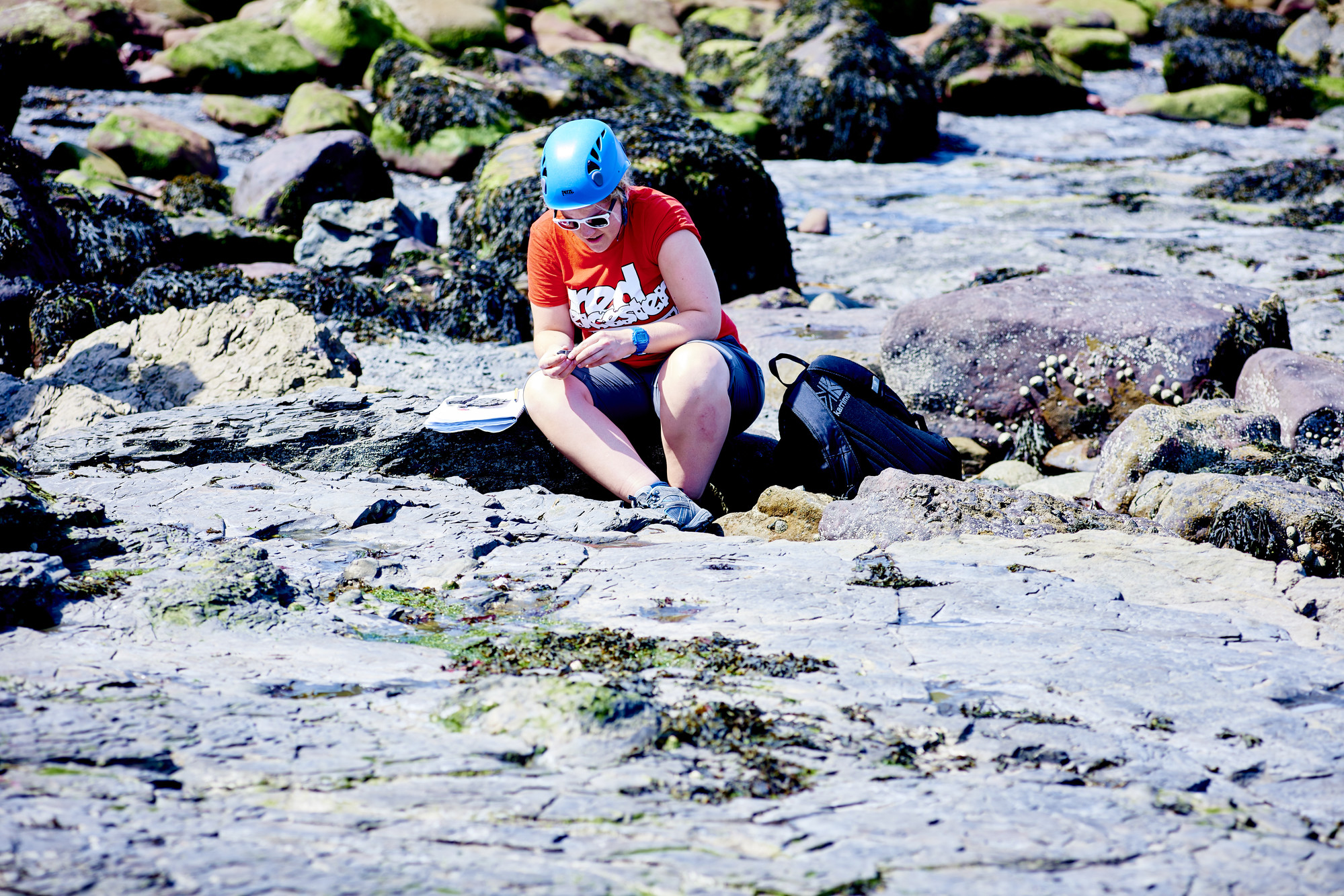 Man writing notes while sat on rocks