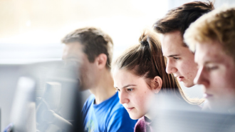 Three students sitting at computers.