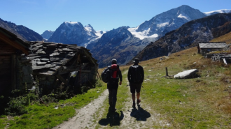 Two students with their backs to the camera looking at some snow capped mountains.