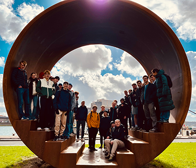 Group of students and staff standing in a cylindrical artwork