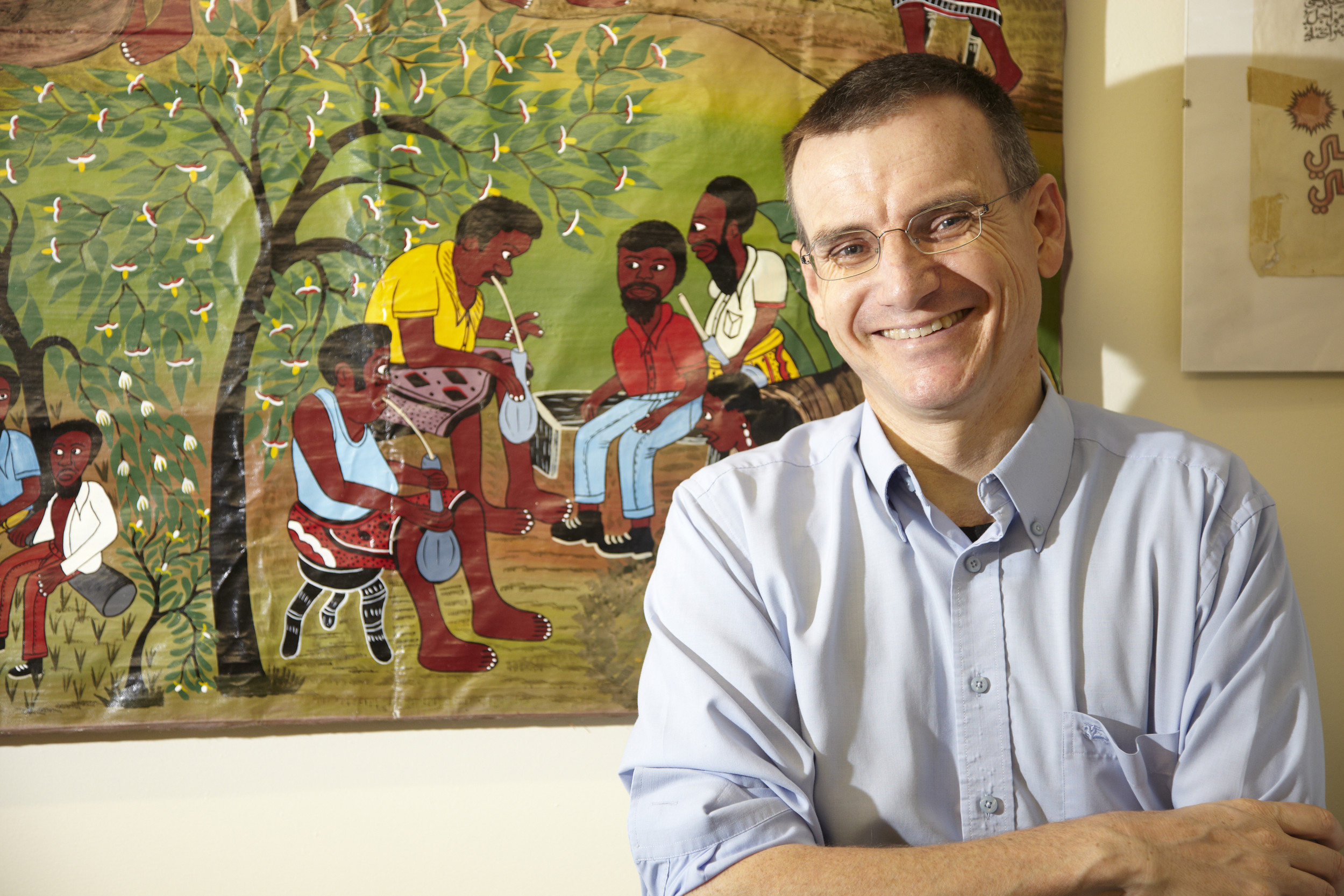 Headshot of a professor in front of aboriginal artwork