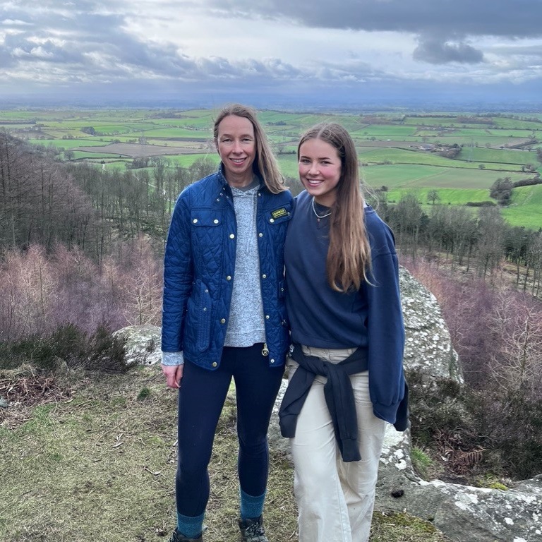 Mother and daughter standing next to each other on a mountain